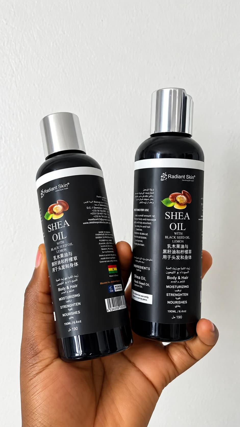 Bottles of Debbitone Brightening Shea Oil held in one hand
