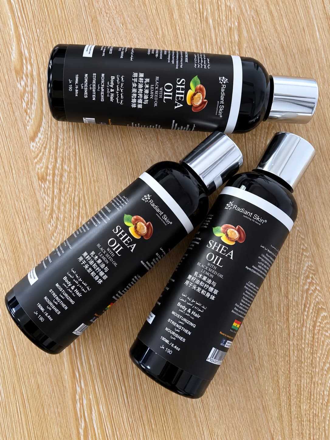 Three bottles of Debbitone Brightening Shea Oil arranged on a wooden surface