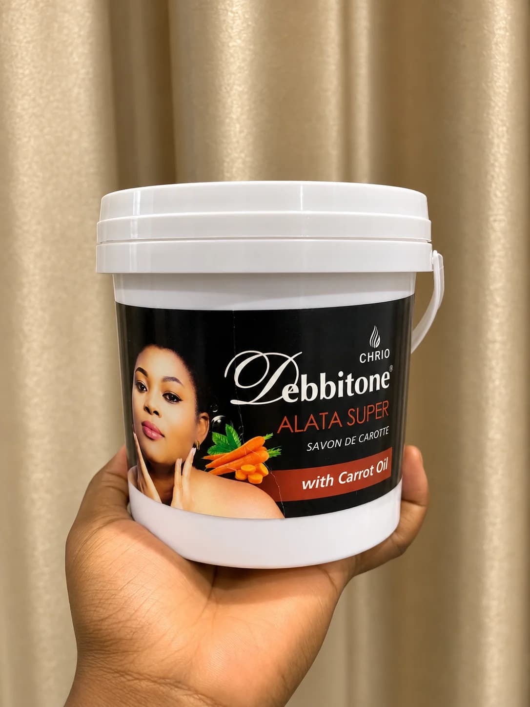 The 1kg Debbitone Carrot Lightening Alata Super Soap bucket held in one hand
