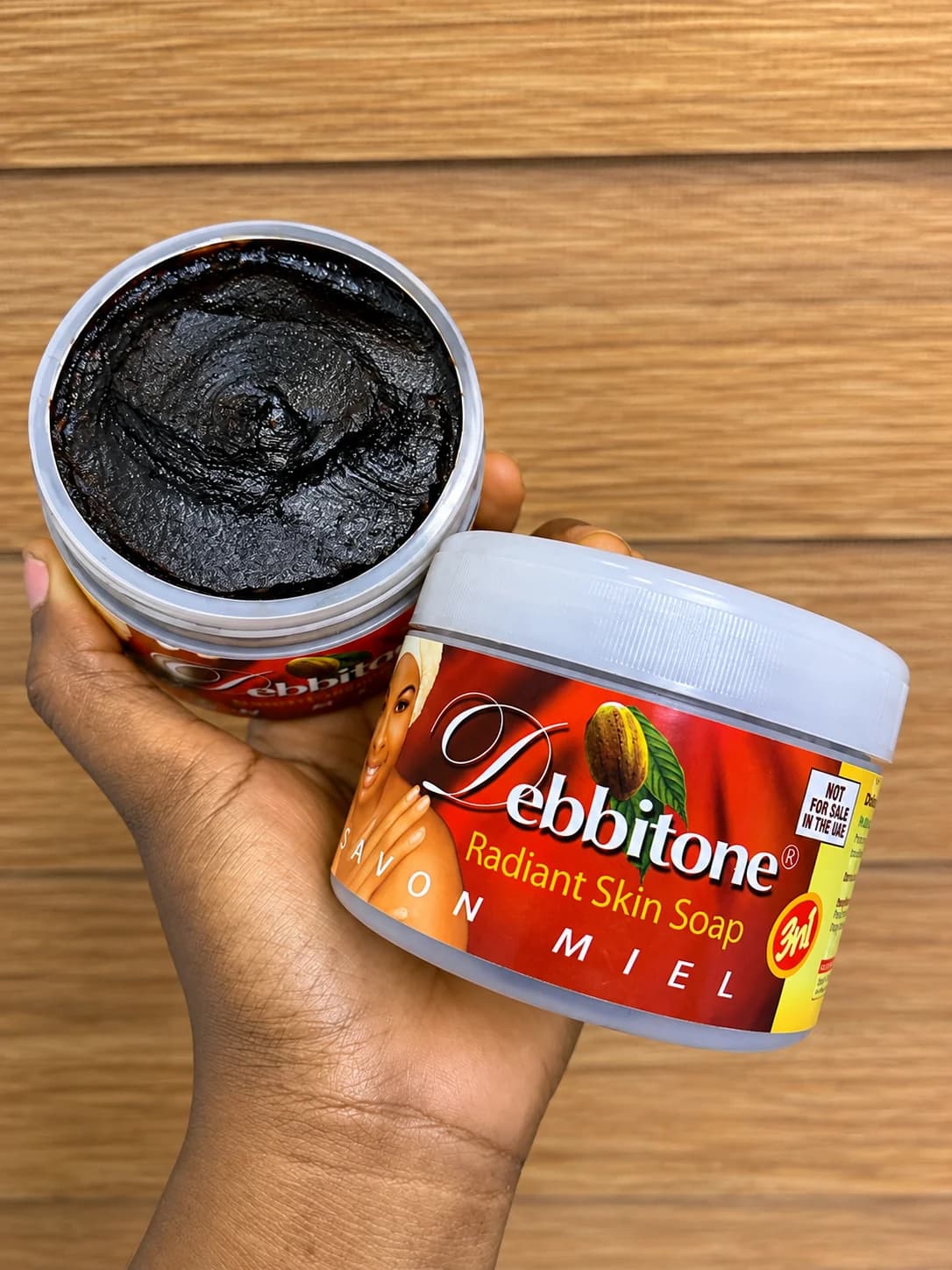 An open tub of Debbitone Radiant Skin Soap showing the rich black soap inside
